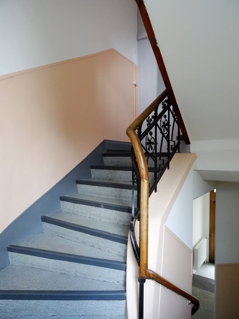 wooden handrail, black metal railing, grey steps, pink wall