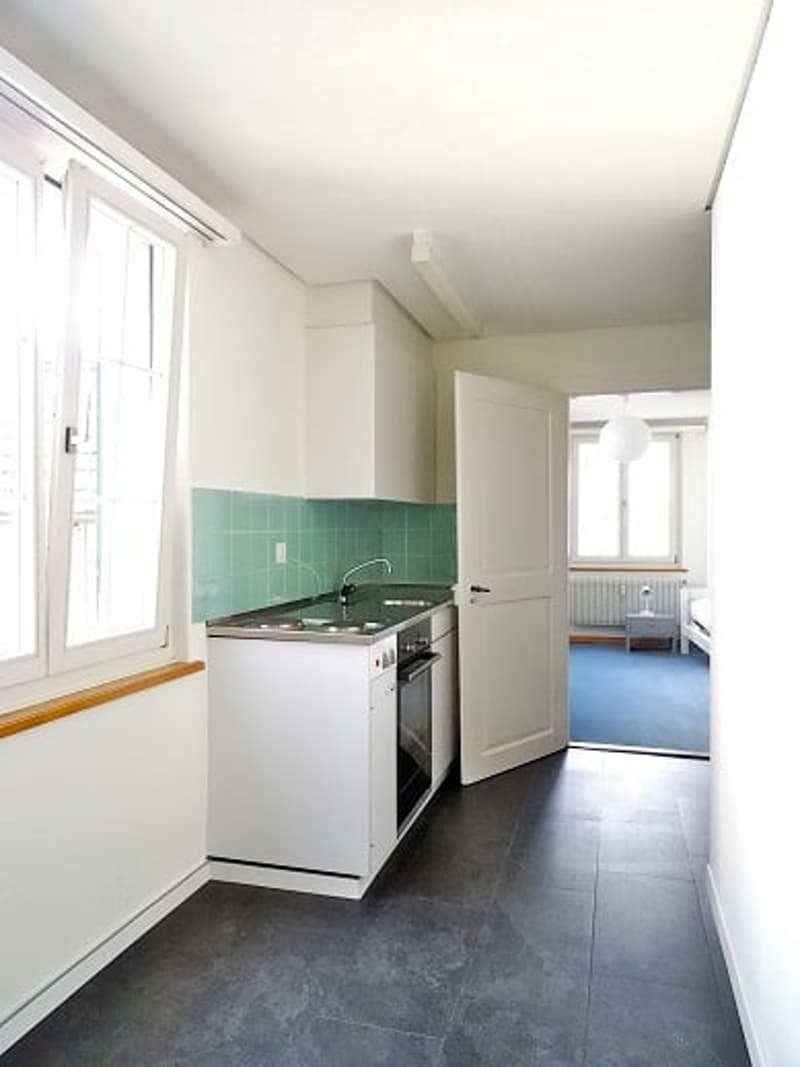 kitchen with white cabinets, green tiles, stainless steel appliances, open door