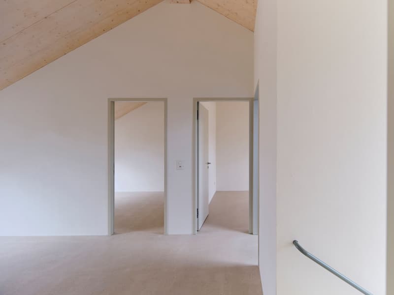 white walls, wooden ceiling, light beige floor, two doors, stairs