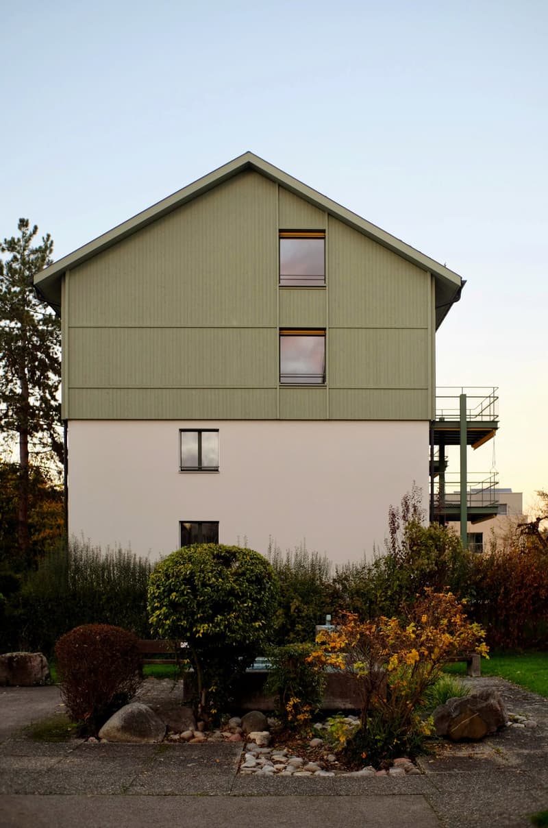 2 story house, green exterior, balcony on the second floor, large windows, well-maintained garden