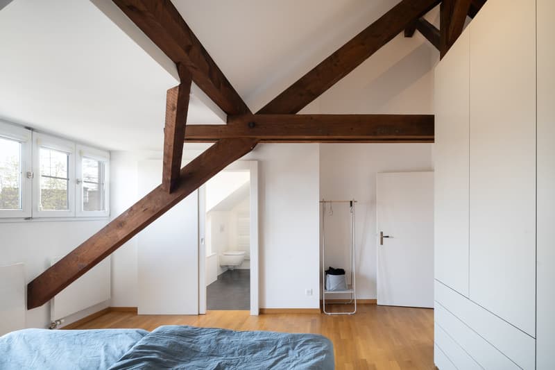 bedroom with wooden beams, wooden floor, white walls, bed, wardrobe, windows