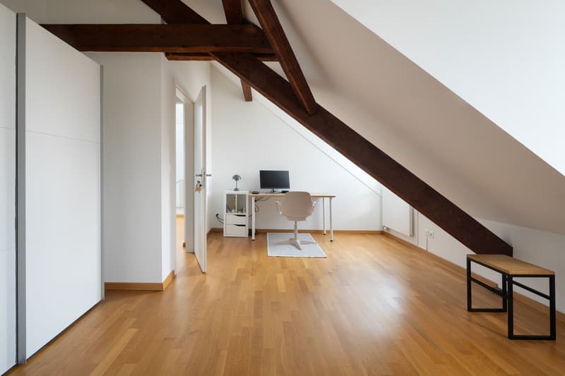 wooden floor, white walls, desk with monitor, chair, small table, bench, radiator