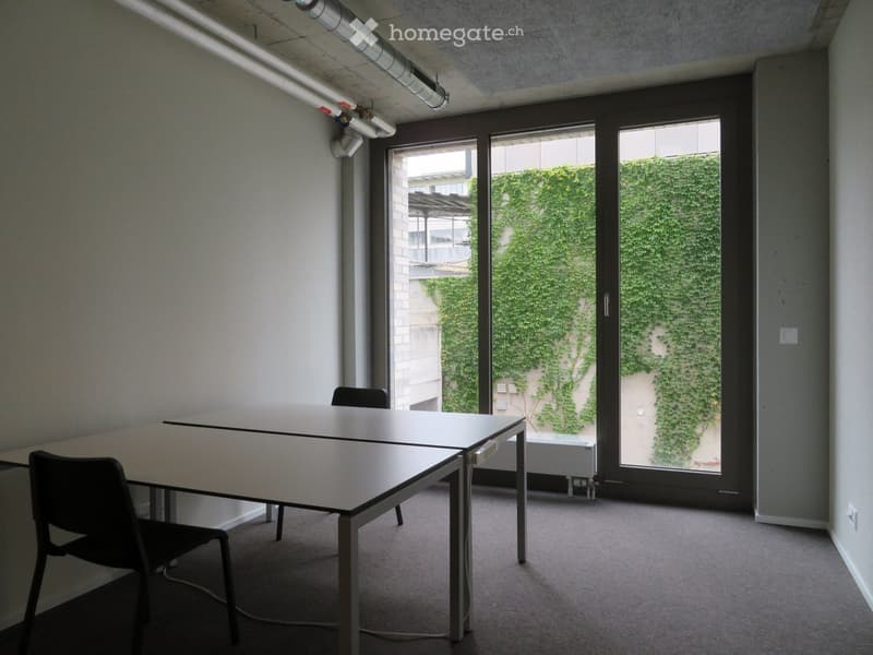 empty office with two tables, sliding door, ivy covered wall outside, power outlets on walls
