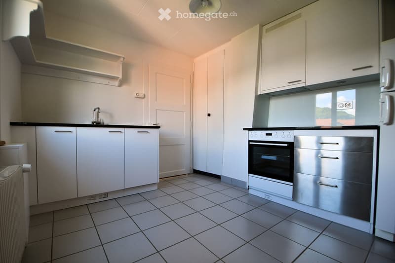 modern kitchen with white cabinetry, black countertops, silver appliance, stainless steel drawer, sink, faucet, oven