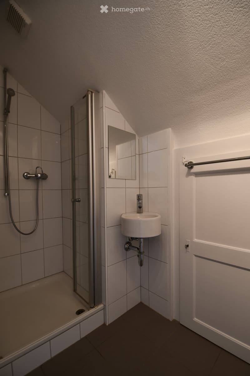 white tiled shower, white sink, mirror, towel rack