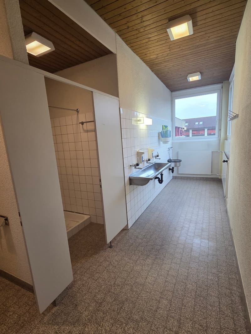 Public bathroom with a shower area, sinks, and toilets.