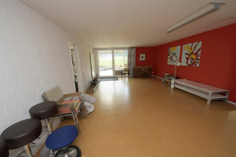 Empty room with white walls, red wall, wooden floor, glass door, bench, stools, picture frame, cabinet, and lamps