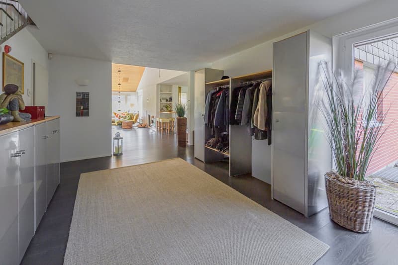 Entrance hall with a rug, built-in wardrobes, a potted plant, and a staircase
