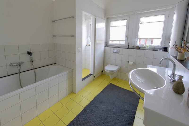 Bathroom with bathtub, toilet, sink, yellow tiles, white tiles, shower, towel rack