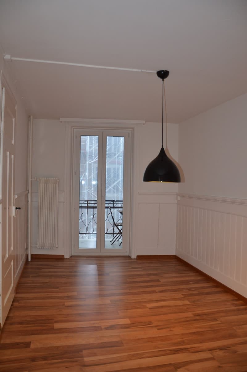 empty room, wooden floor, white walls, sliding glass door, balcony, radiator, pendant lamp