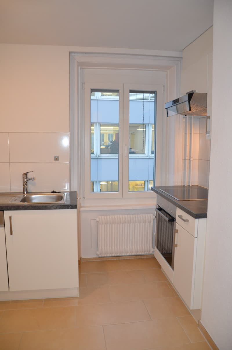 modern kitchen with white cabinets, stainless steel sink, gas stove, oven, and a window with a view