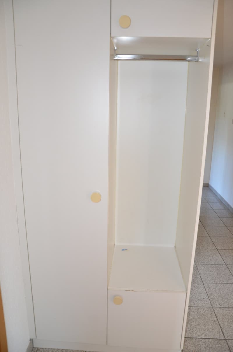 white wardrobe with hanging rod, two drawers, tiled floor