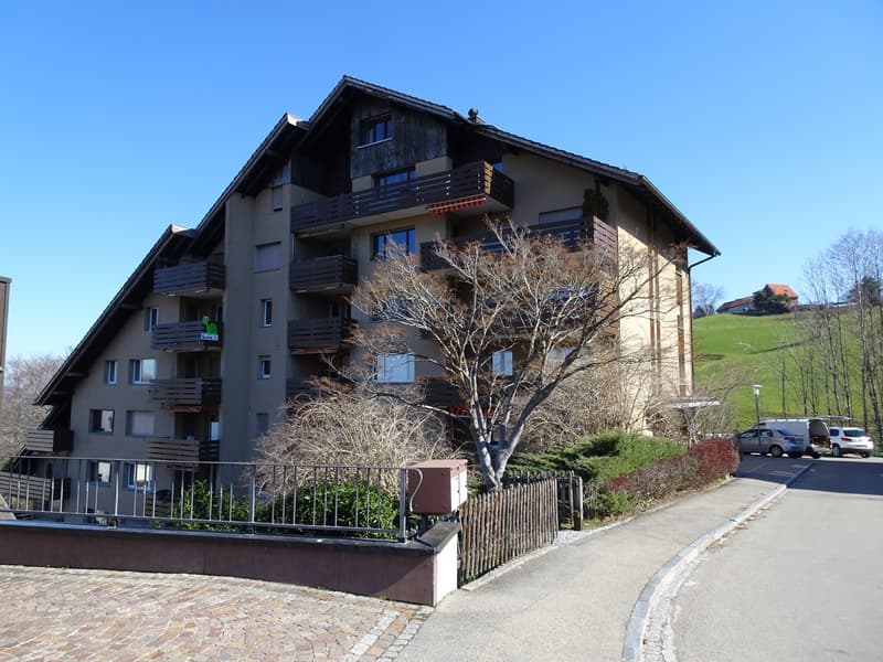 3 story building, many balconies, brick ground floor, car parked outside
