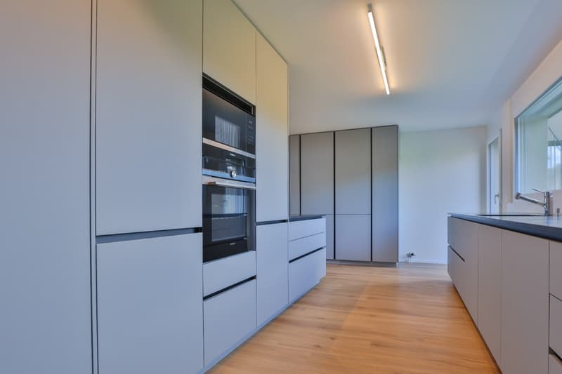 modern kitchen with white cabinetry, wooden floor, appliances integrated, open design, bright natural light from windows