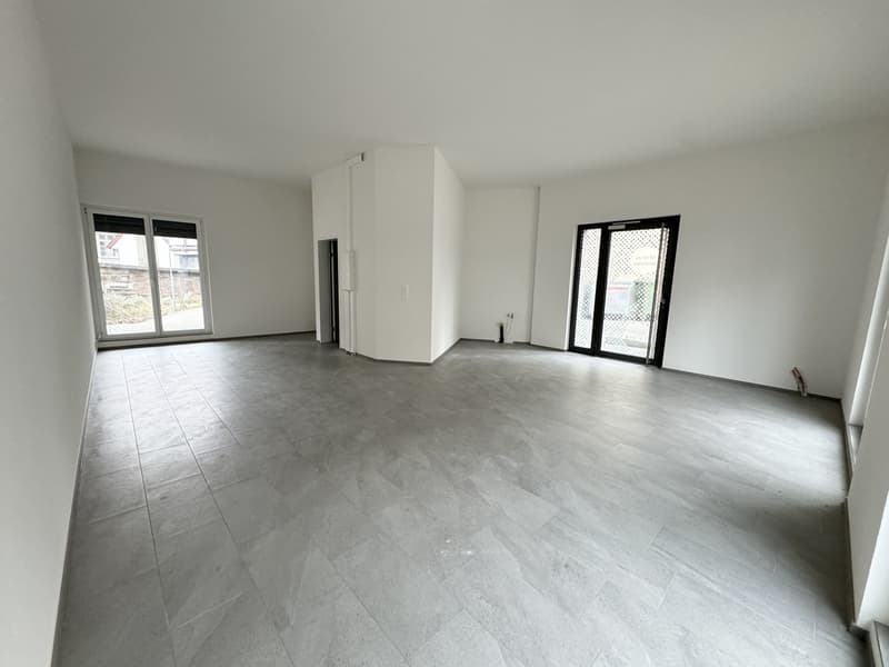 Empty room with white walls, gray tiled floor, two glass doors, and a window.