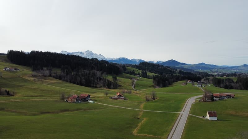 Green hills, small houses, road, mountains in the background