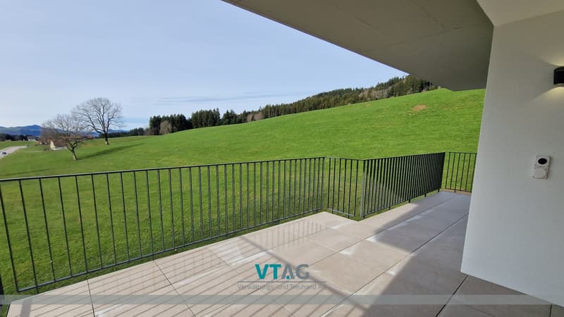 Balcony with metal railings, tiled floor, view of a green field and trees