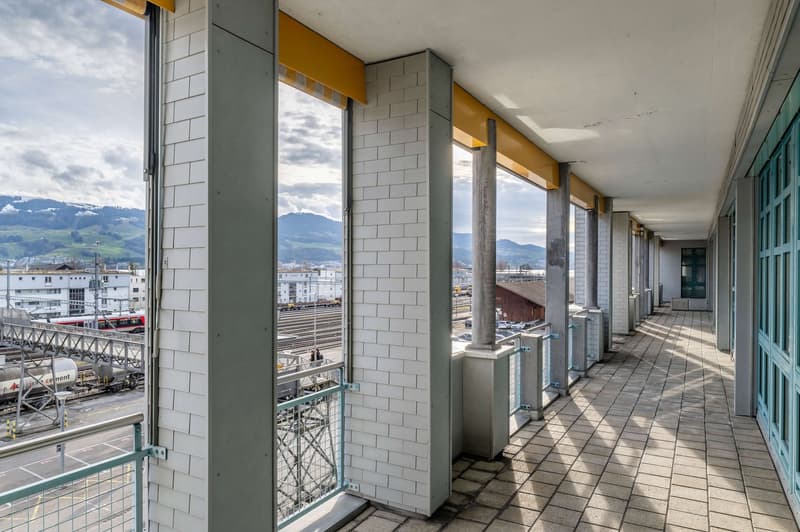 Corridor with rows of doors, balconies, tile floor, city view, mountains view