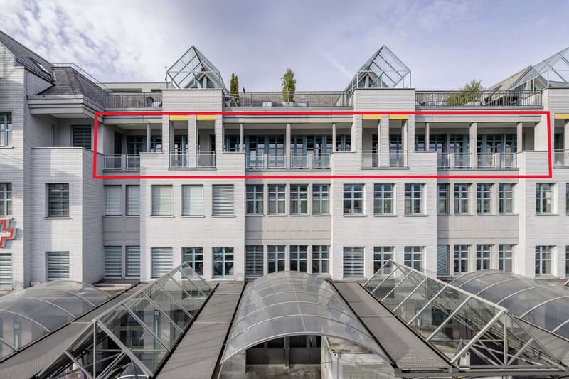 modern multi-storey building, white brick facade, numerous windows, highlighted second floor with balconies