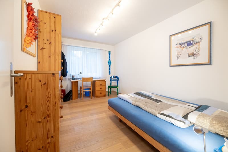 bedroom with wooden floor, bed, desk, chair, lamp, picture frame, window with curtain