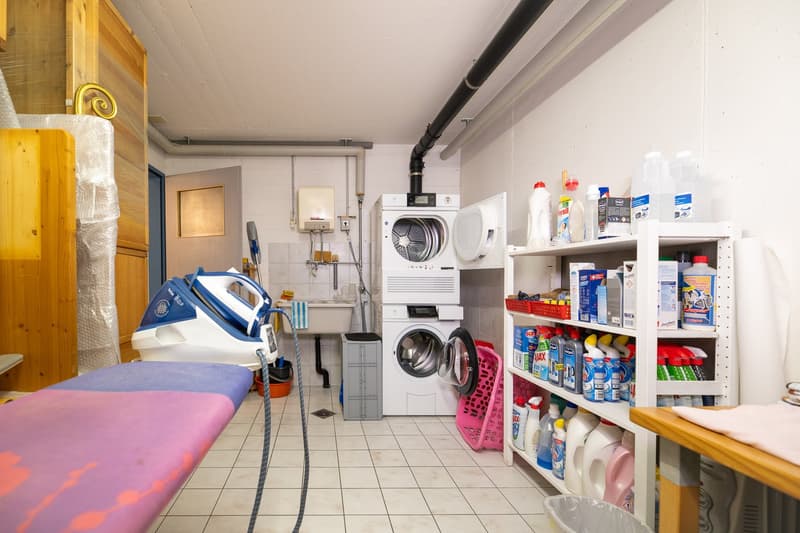 Laundry room with washing machine, dryer, ironing board, cleaning products, sink, and storage shelves