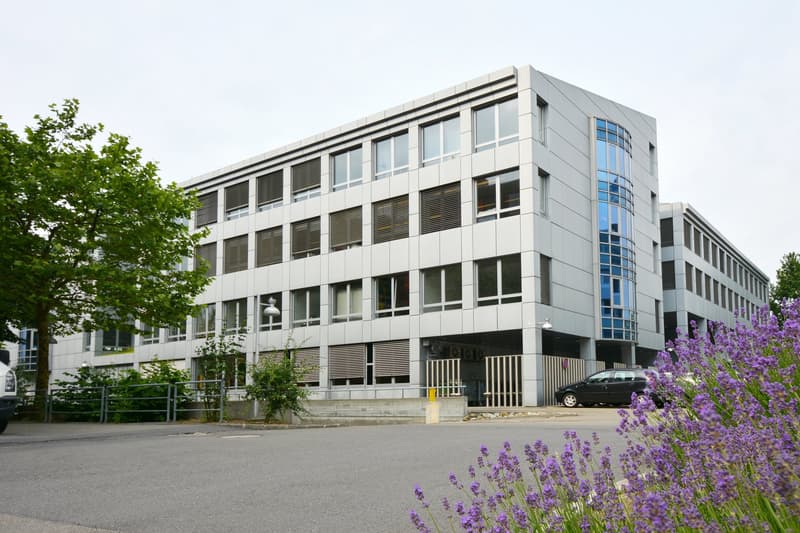 modern office building, multiple floors, white facade, several windows, car parked in front