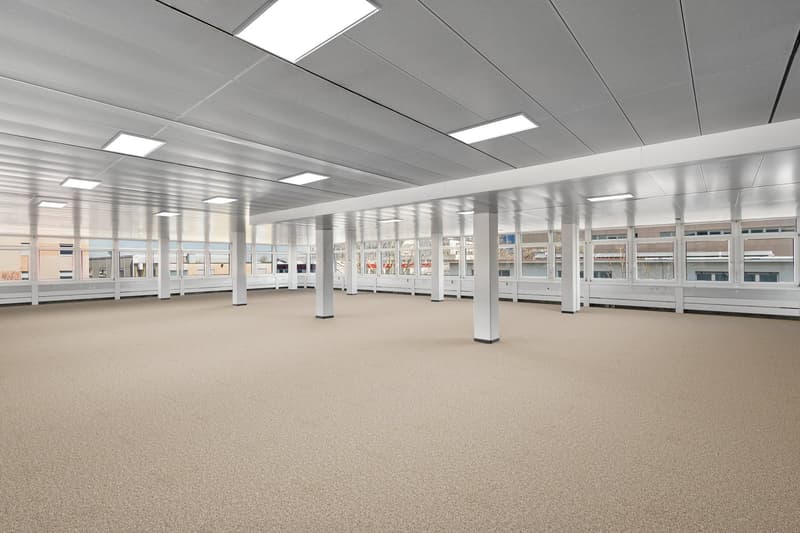 an empty room with carpet flooring and large windows