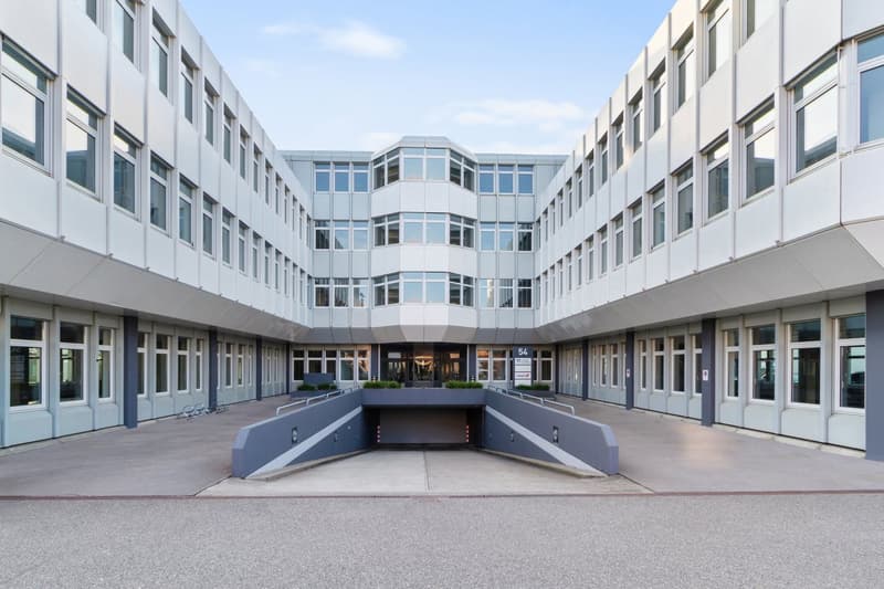 Modern office building, white exterior, multiple floors, large windows, underground parking
