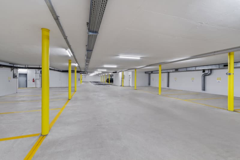 underground parking lot, yellow columns, white walls, gray concrete floor