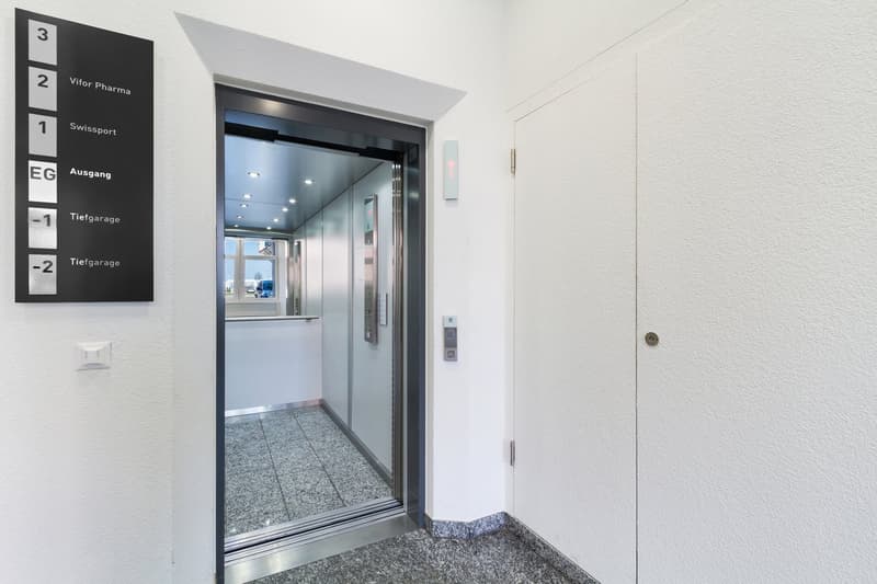 Entrance to a building with an elevator, sign indicating floors and basement garage