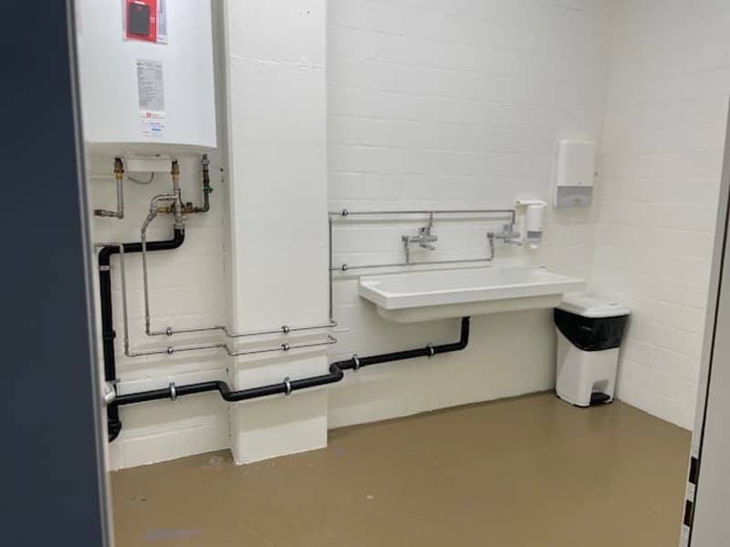 The image shows a utility room with a sink, plumbing fixtures, and a dishwasher visible.