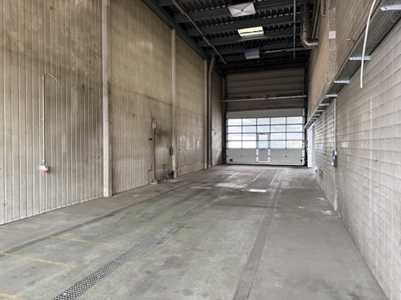 Large empty room, concrete floor, walls, glass windows, pipe on ceiling
