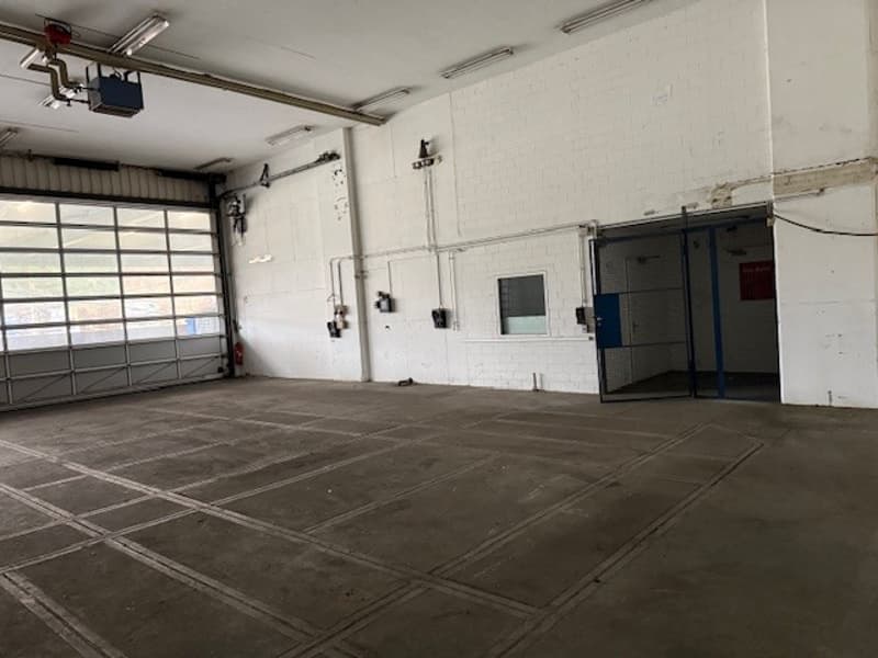 large empty room with concrete floor, two garage doors, two small entry doors