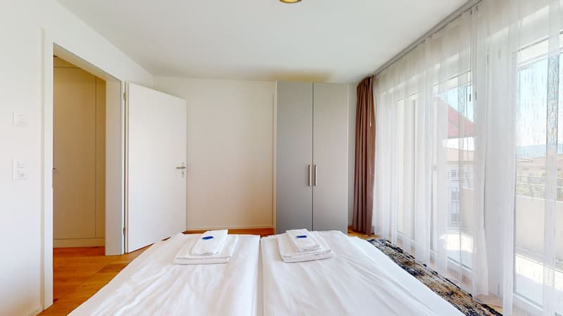 Large bedroom with double bed, large windows, wardrobes, rug