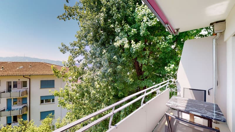 Metal railings, table and chairs on balcony with marble top, balcony has view of tree and mountains