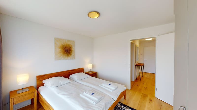Two twin beds, night stands, lamps, artwork on wall, wooden floor