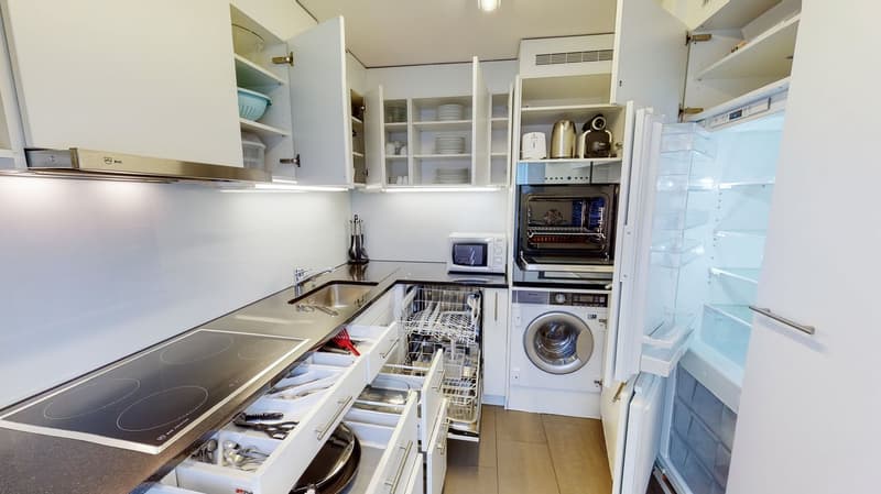 Open plan modern kitchen, white cabinets, tiled flooring, kitchen appliances, stove, dishwasher, washing machine, open fridge