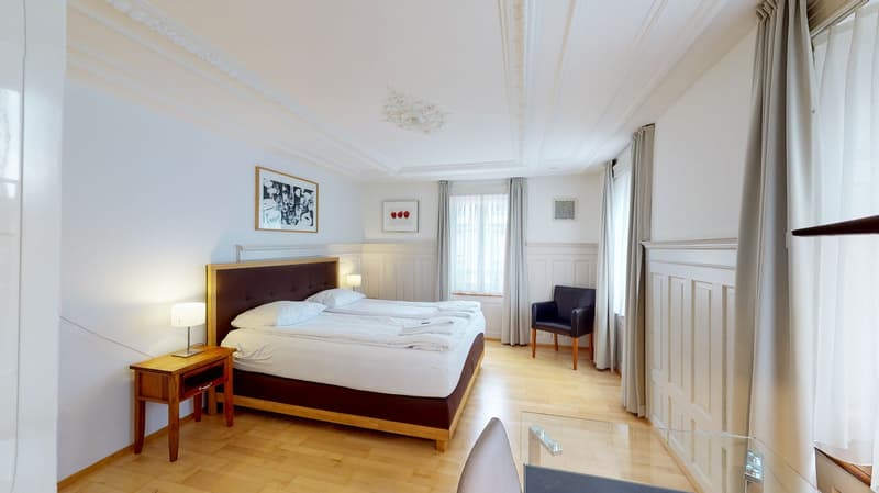 Double bed, night table with lamp, framed picture, window, armchair
