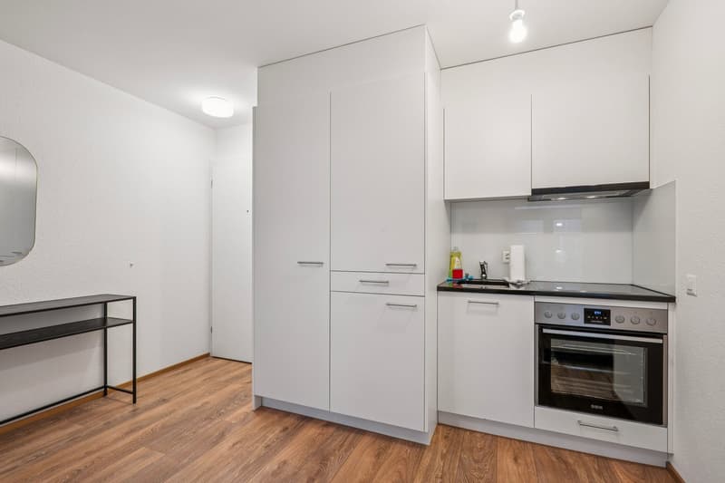minimalistic kitchen, black and white countertop, built-in oven and microwave, washing machine