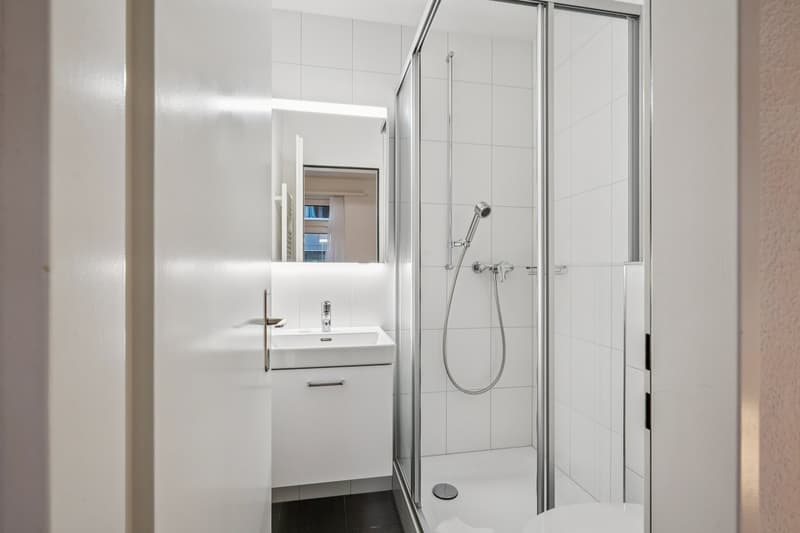 tiled walls, walk-in shower, white sink, toilet, mirror