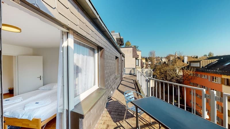 bedroom with single bed, balcony with outdoor table, city view
