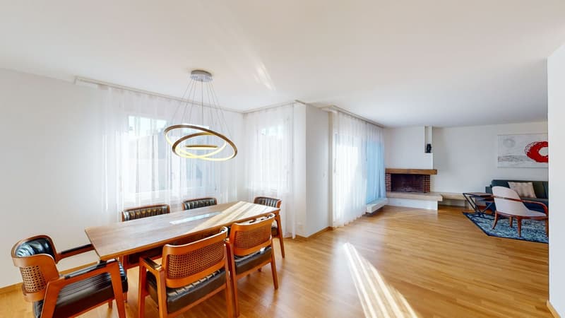 Wooden dining table, wooden chairs, chandelier, hardwood floor, fireplace in adjacent living room, white curtains