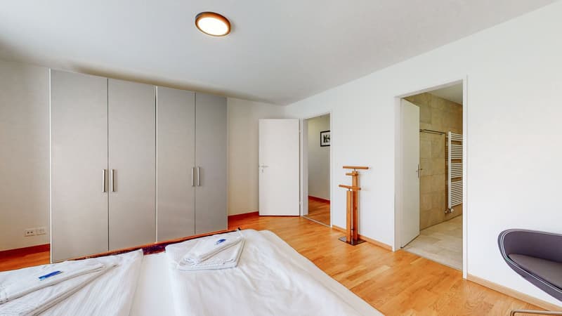 Modern room with hardwood floor, white walls, fitted wardrobe, double bed, two entrances