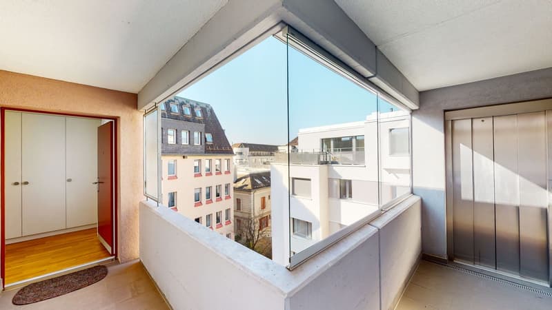 A balcony with glass railings and large glass walls showing the view outside