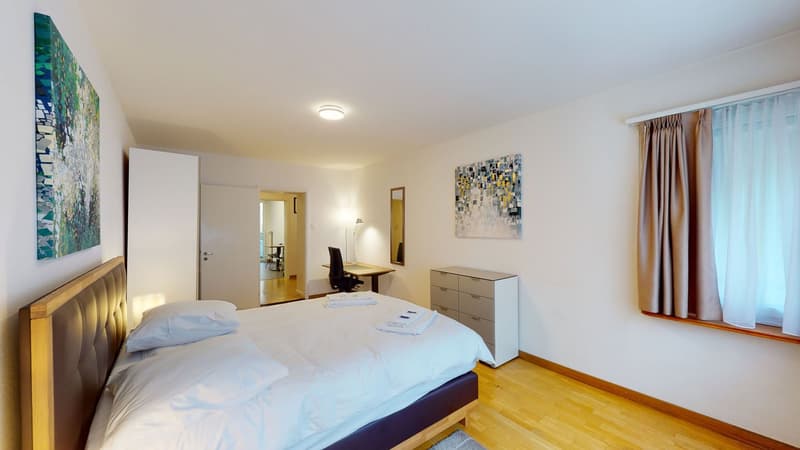 Double bed, leather headboard, night stands, 2 white pillows, desk, chair, mirror, chest of drawers, artwork, curtains, lamps