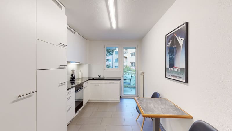 open plan kitchen, white tiles, open sliding door to balcony, white cabinets, electric stove, oven