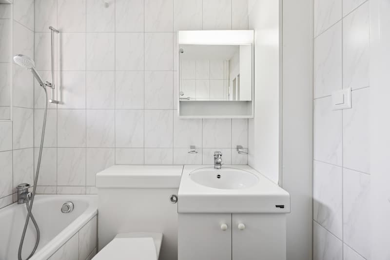 Bathtub, toilet, sink, mirror, shower head and hose, fully tiled walls