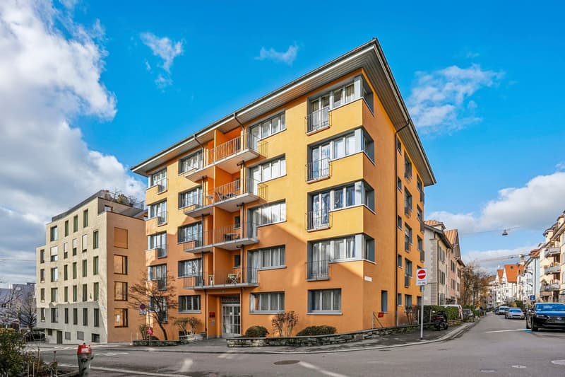 modern apartment building, yellow facade, multiple balconies, glass windows, street view
