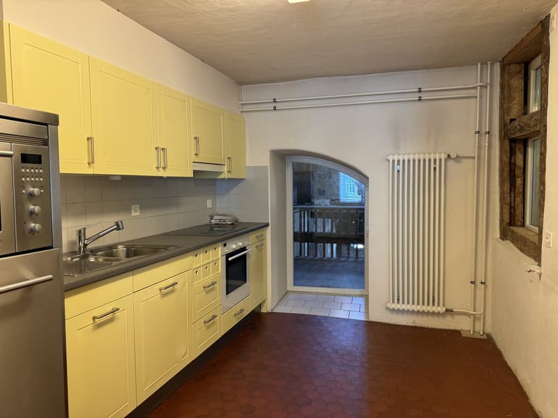 Tiled floors, yellow cabinetry, black granite countertops, built-in appliances, open archway