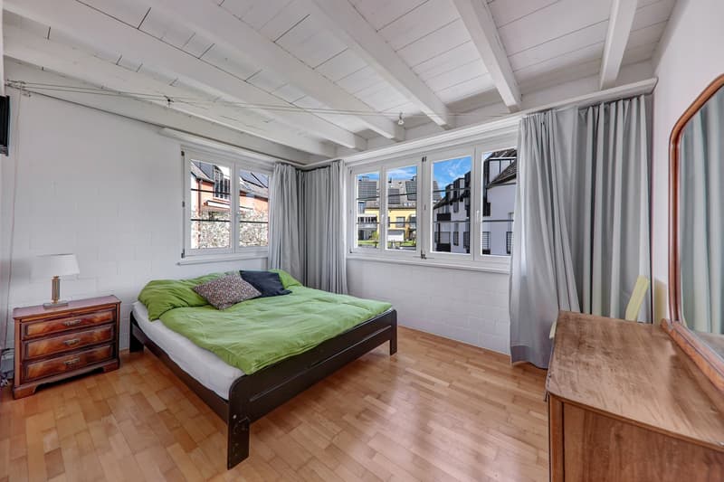 bedroom with bed, wooden furniture, windows, lamp, mirror